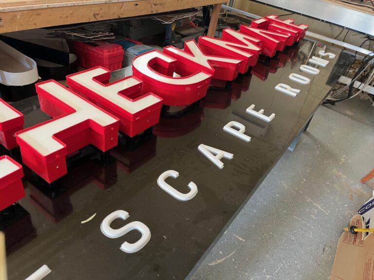 Red Checkmate Escape Rooms channel letters and push-through panel in fabrication for a Land O' Lakes location